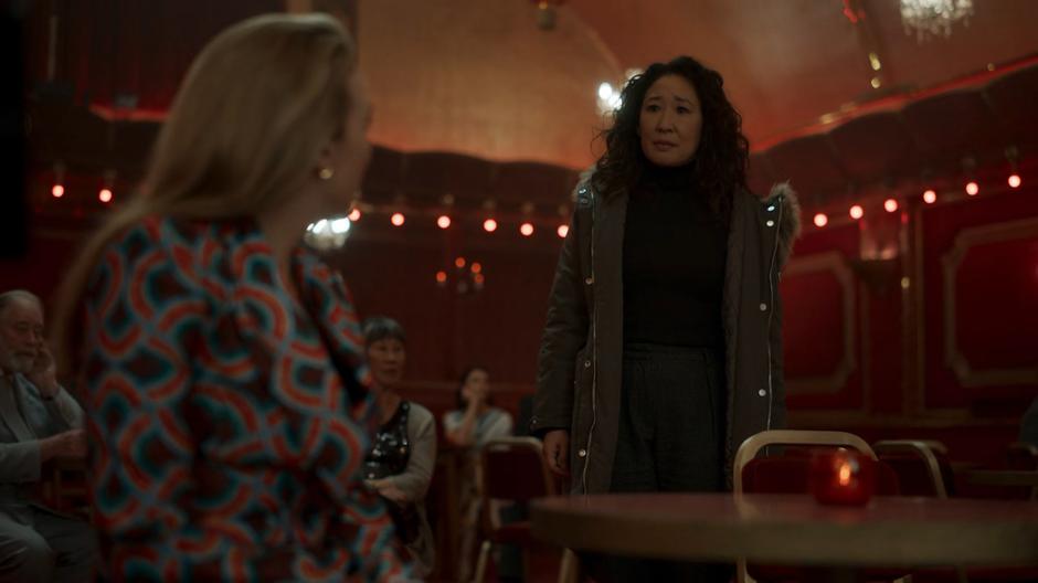 Villanelle turns and looks at Eve as she approaches the table.