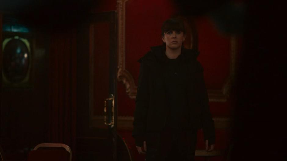 Rhian enters the ballroom from a side door and searches for Villanelle.