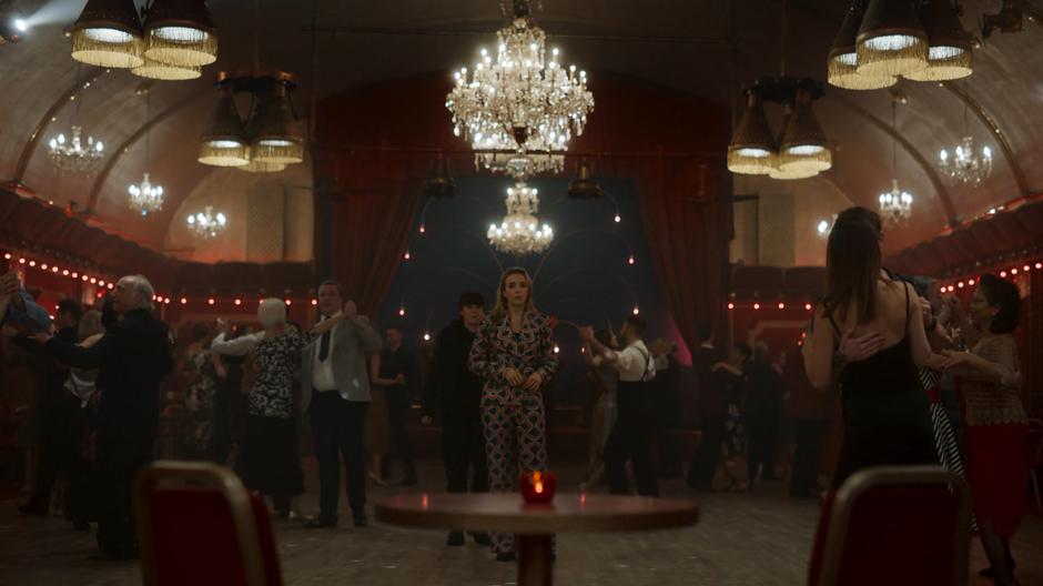 Villanelle watches Eve leave while Rhian comes up behind her on the dance floor.