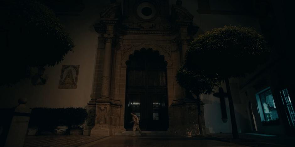 Ava runs past the front doors of the chuch in the dark.