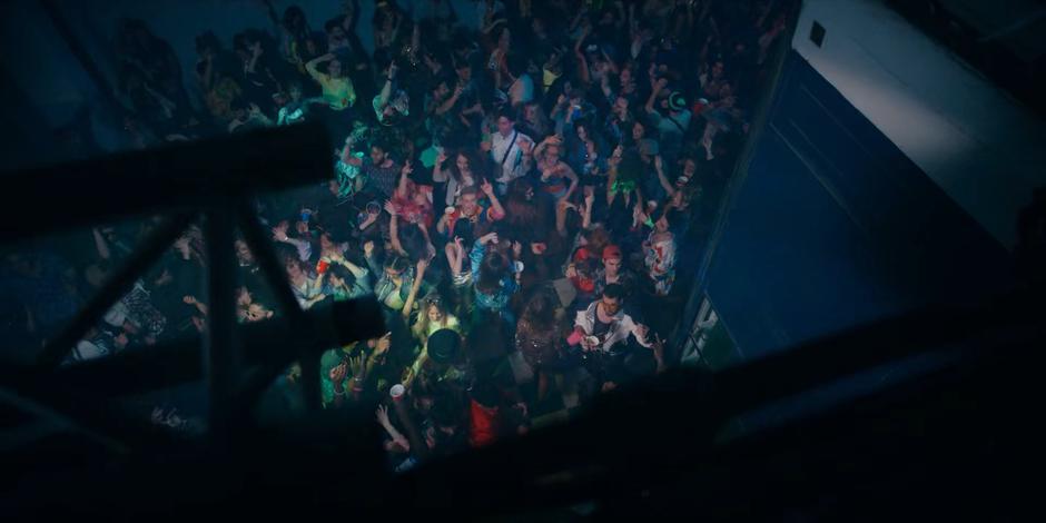 People dance packed together under the flashing lights of the rave.