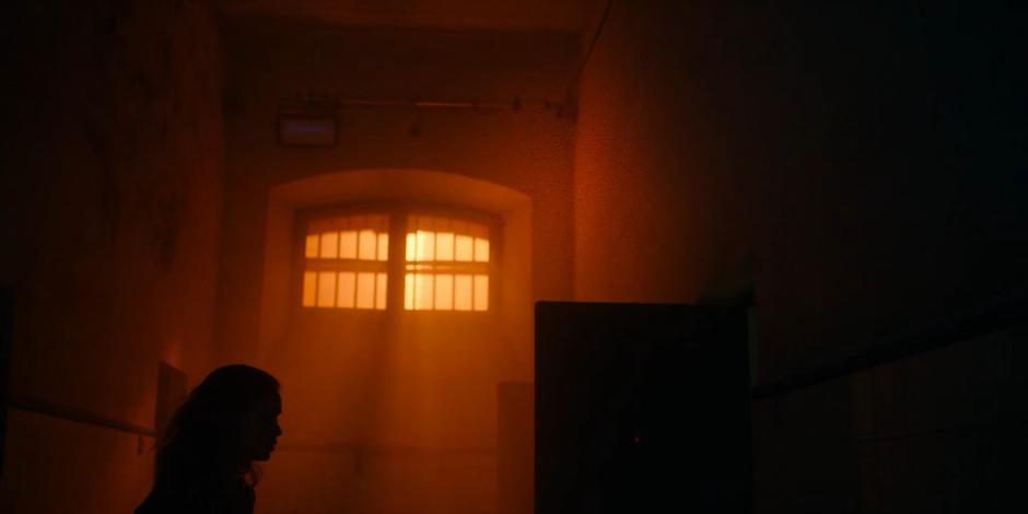 Ava looks into one of the prison cells after following the strange red cloud and sees someone on the floor doing drugs.