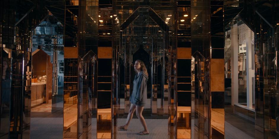 Ava wanders through a mirror-covered room in the villa.