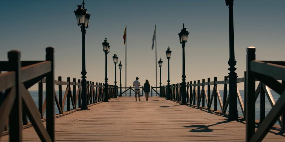 JC and Ava walk down to the end of the pier talking.