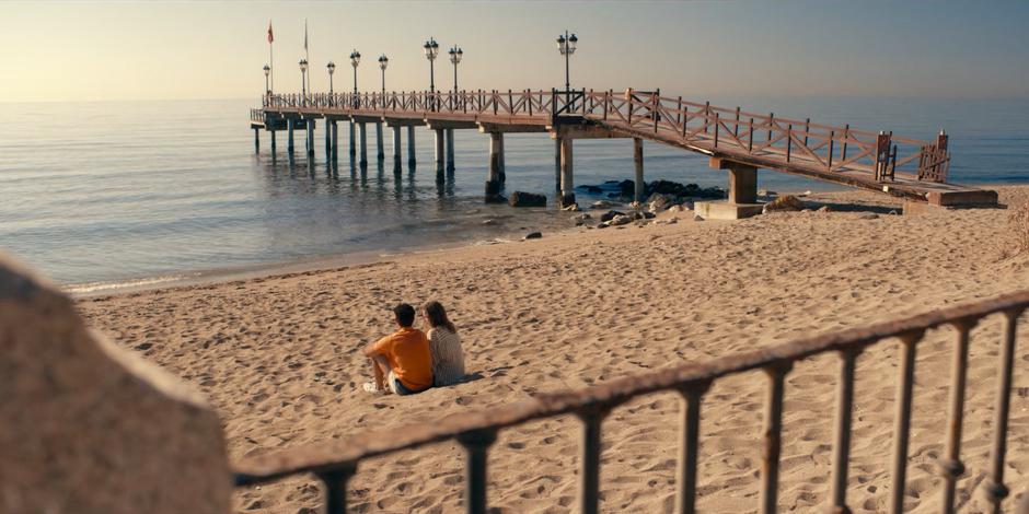 JC sits down next to Ava on the beach to talk.