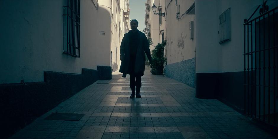 Mary walks down the alley towards the cafe.