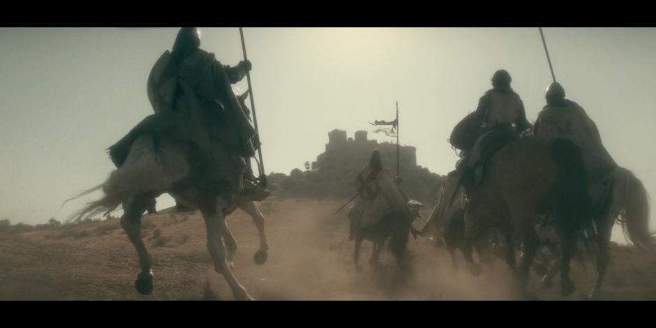 Riders race up the hill towards the castle.