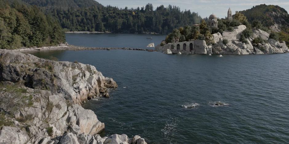 Establishing shot of Safiyah's villa separated by a land-bridge from the beach.