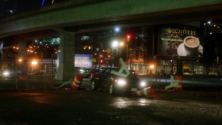 Joe's car crahes through a construction barrier as he swerves off the road.