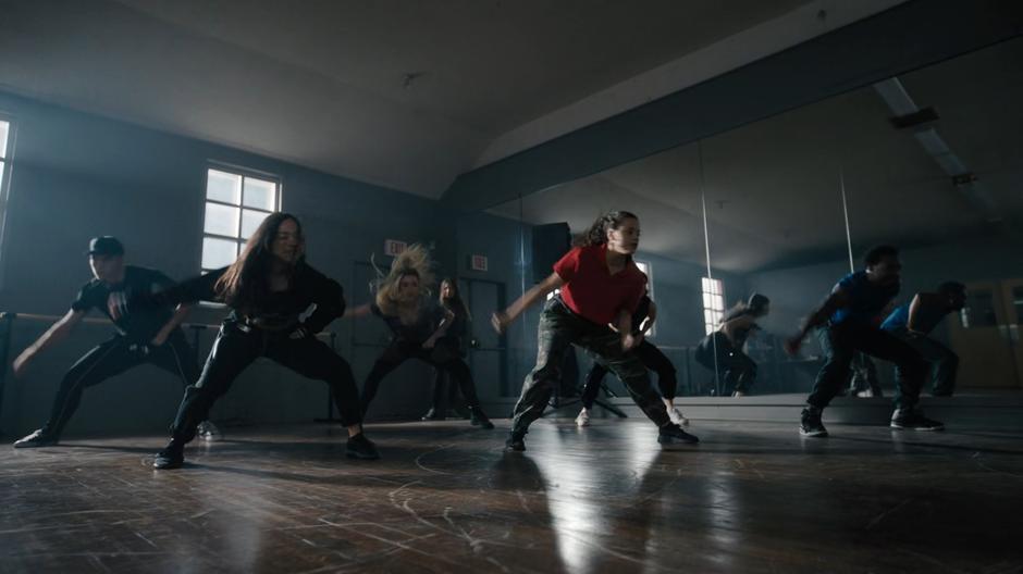 Maggie dances with a group of people in front of a mirror.