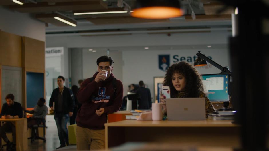 Antonio takes a drink of his coffee when Maggie sees something on her phone.