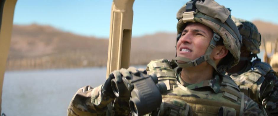 Joaquin follows Sam in the sky from the humvee through his binoculars.