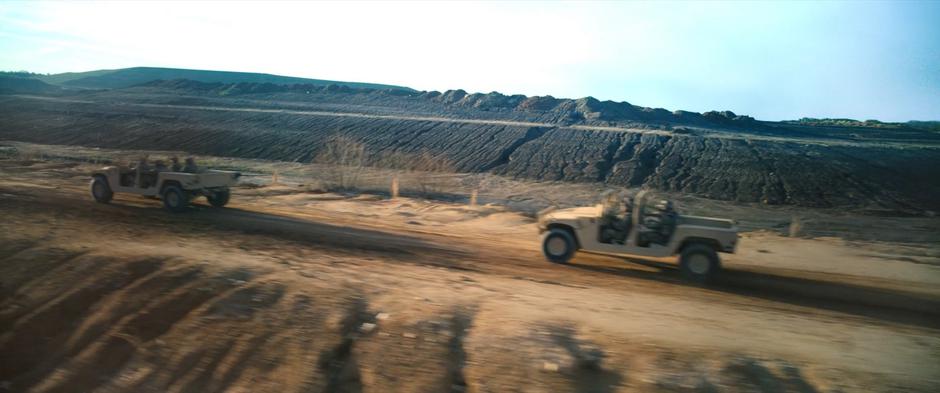 Two humvees drive across the desert following Sam's path.