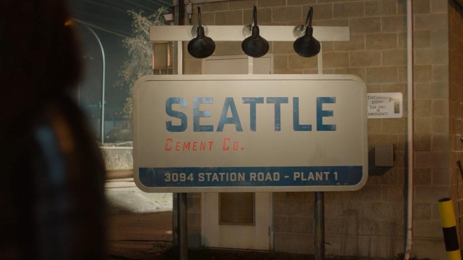 A sign for the Seattle Cement Co. sits beneath some lights.