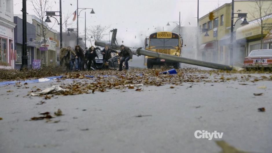 The survivors run around the downed power pole while the town disappears behind them.