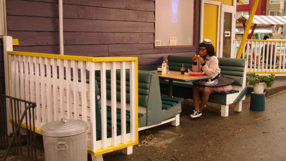 Sandy eats her lunch at a table by the side of the restaurant.