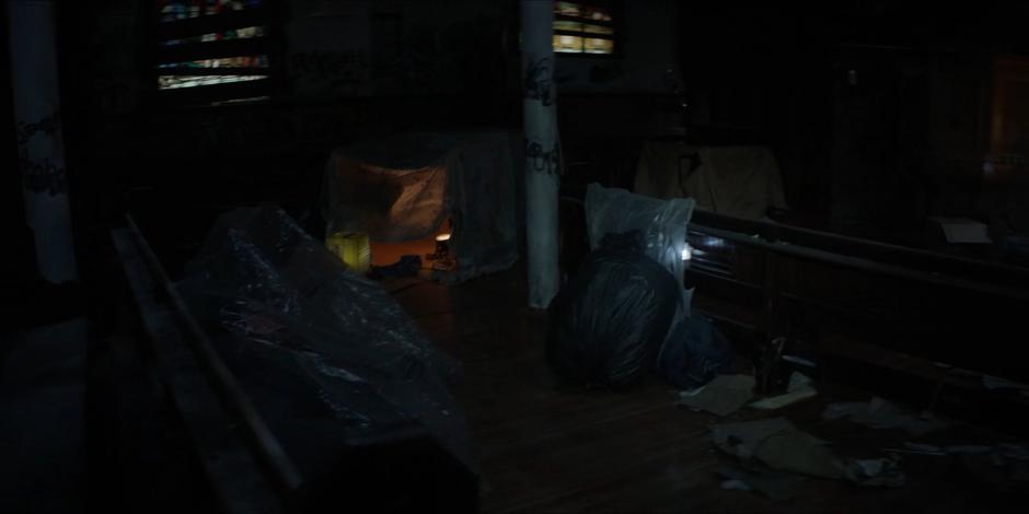Ryan's flashlight illuminates trash covering the floor of the derelict church.