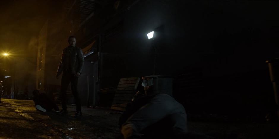 John Diggle stands between Luke and Tavaroff to protect Luke.