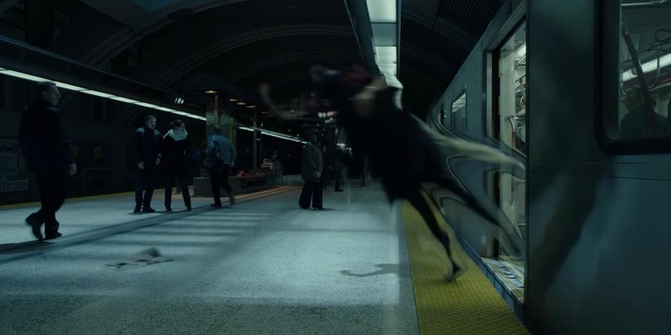 The two people fighting jump away as they leap out of the train onto the platform.