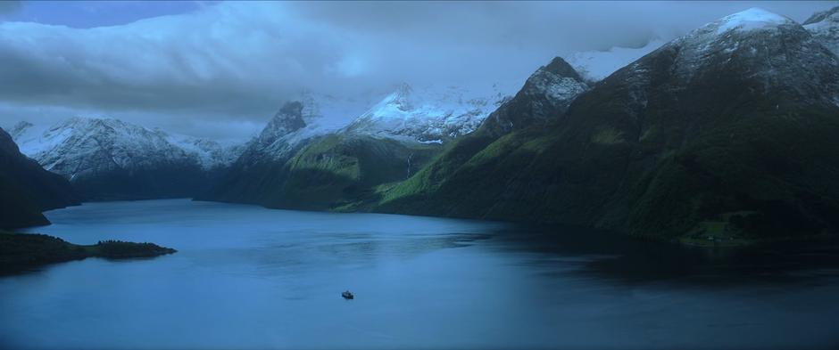 The ferry floats down the middle of a fjord.