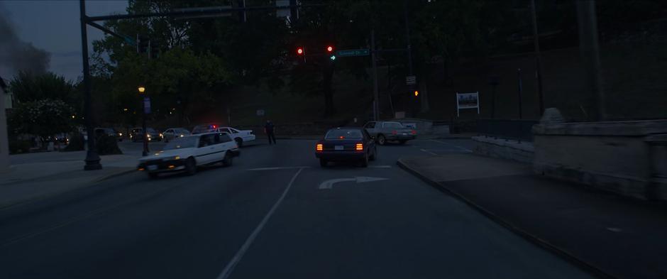 A police officer directs traffic at the intersection ahead of the car.