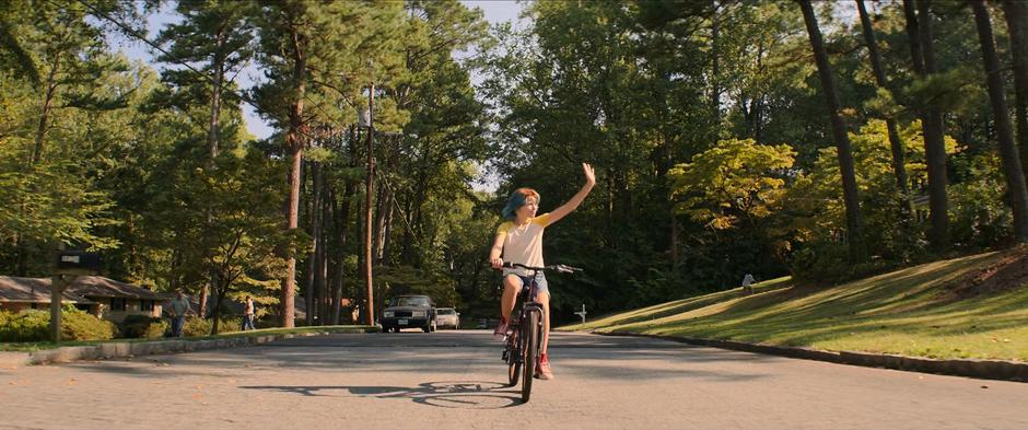 Young Natasha waves at some neighborhood kids as she bikes past.