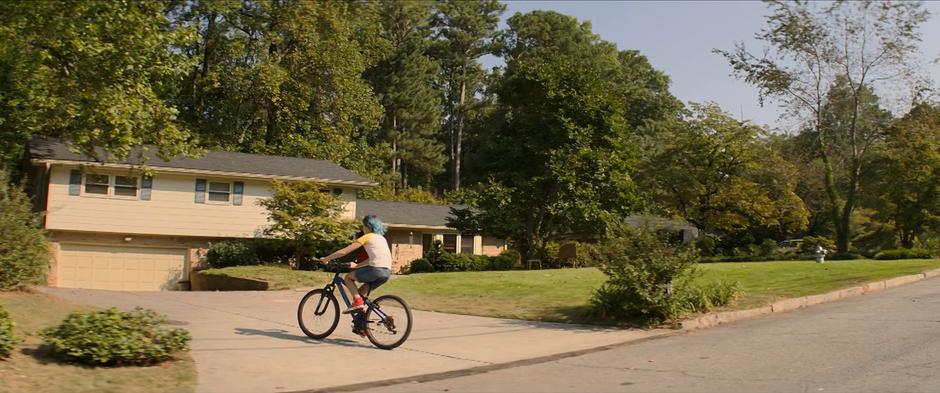 Natasha turns off the street and rides her bike into the driveway.