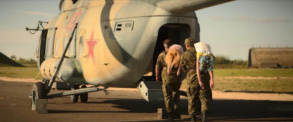 Two soldiers carry the unconcious bodies of Yelena and Natasha into a waiting helicopter.