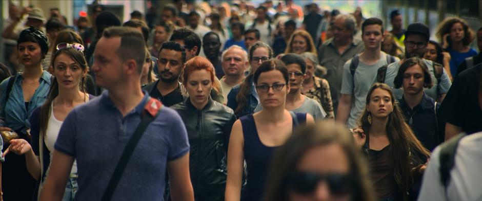 Natasha walks with the crowd out of the station.