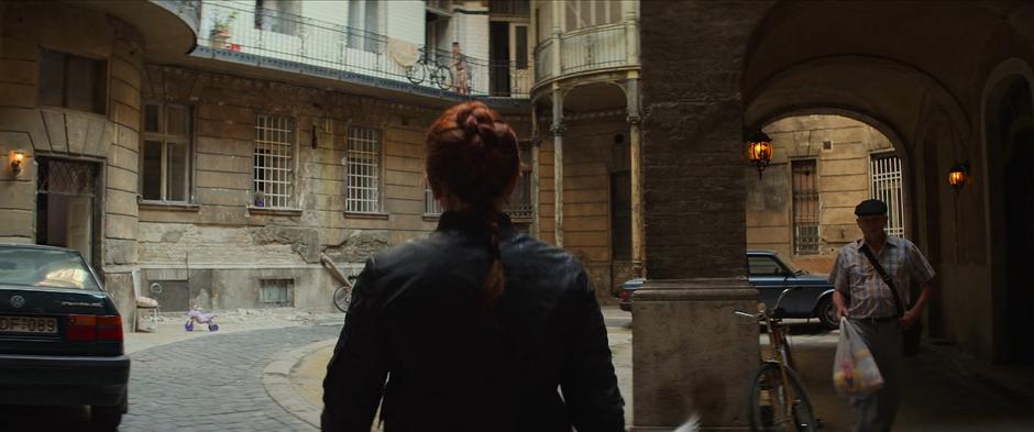 Natasha looks around the courtyard as she heads towards the elevator.