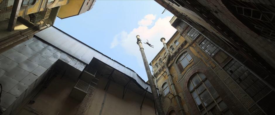 Ingrid leaps towards the chimney carrying Natasha and Yelena away as it falls over.