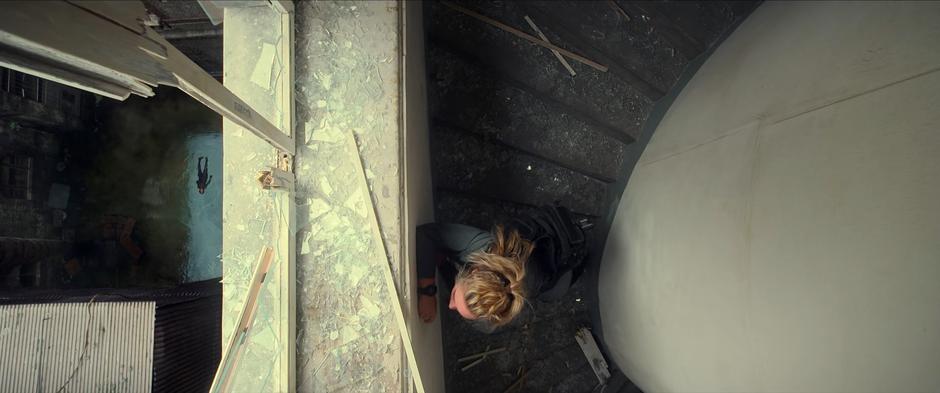 Yelena stands up from where she landed on a staircase high above as Ingrid lies in a pool of water in the courtyard below.