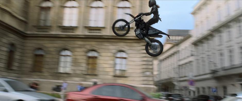 The pursuing Widow leaps through the air on her motorcycle.