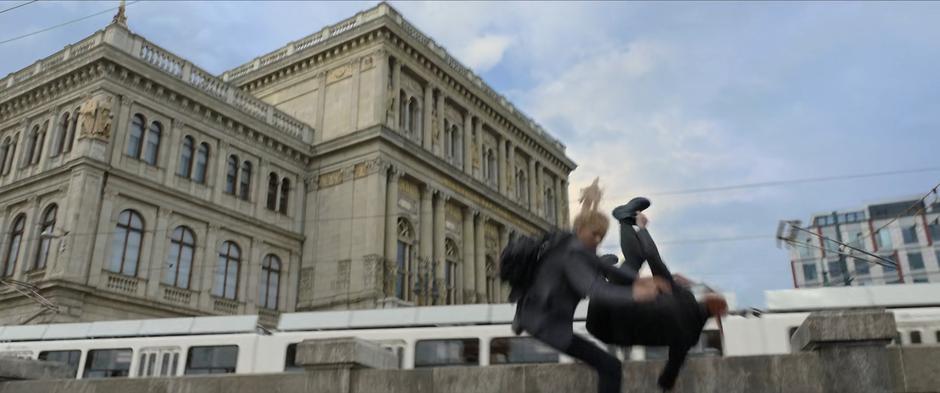 Yelena and Natasha flip over the barrier after flying off their bike.