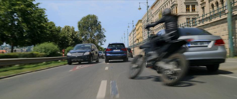 A Widow weaves through traffic on her motorcycle to follow the newly stolen car.