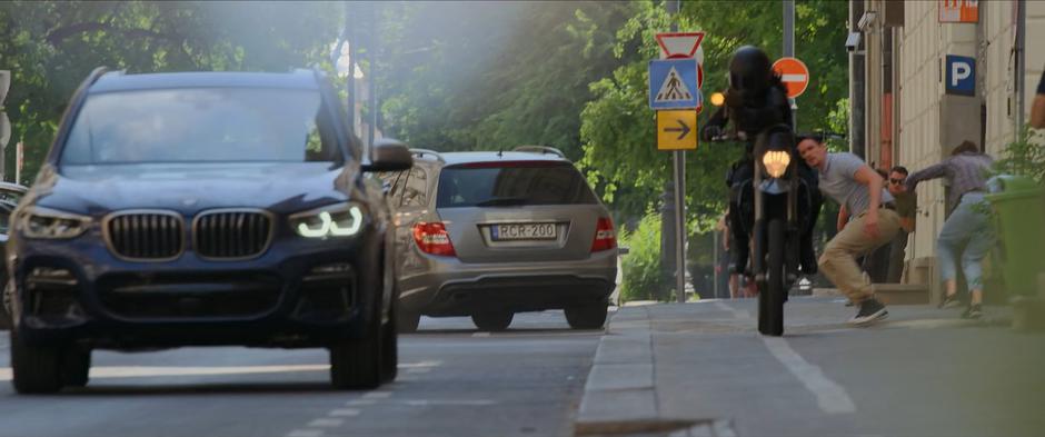 The Widow fires from her motorcycle at the stolen car containing Yelena and Natasha.