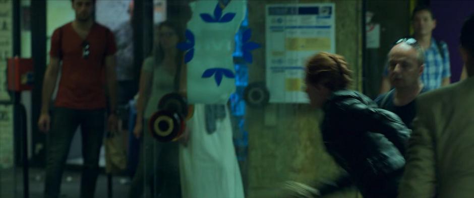 Natasha races away from the car towards the escalators as people watch.