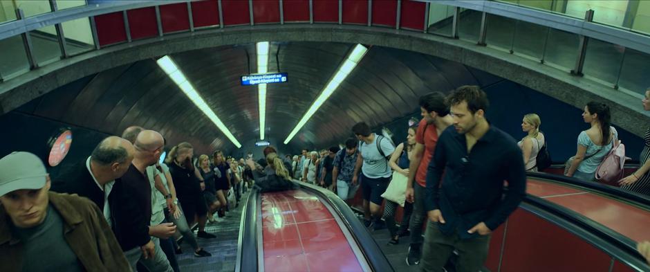 People watch Natasha and Yelena slide past on the escalator divider towards the platform.