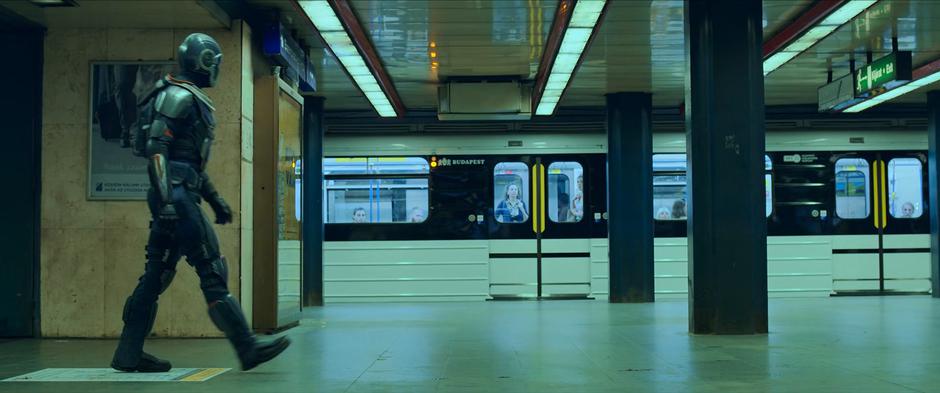 Taskmaster looks around the platform for Natasha and Yelena as a train leaves.