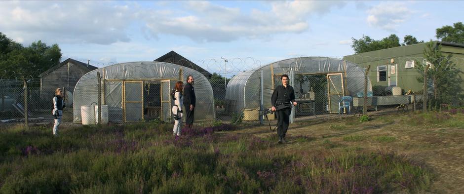 Melina walks past Yelena, Natasha, and Alexei towards her house.