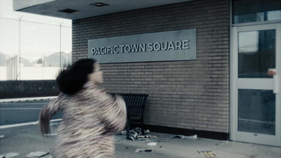 Maggie runs towards the entrance of the mall on the roof of the parking garage.