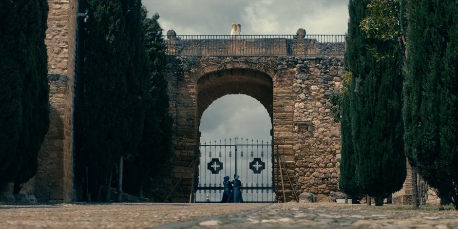 Two nuns are visible in the distance closing and locking the gate.