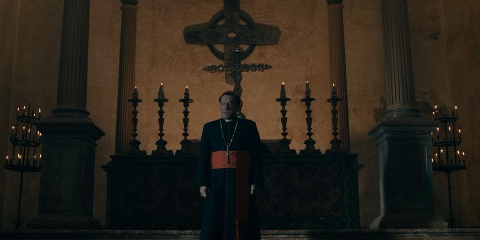 Cardinal Duretti stands in front of the nuns giving a speech.