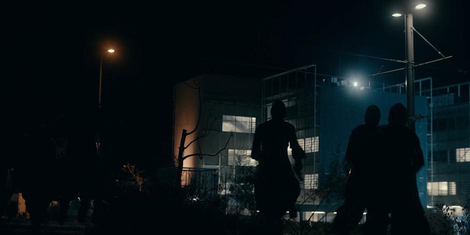 The nuns run across the ground towards the fence surrounding the building.