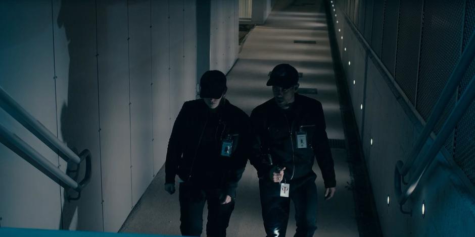 Two guards patrol around the outside of the lab building.