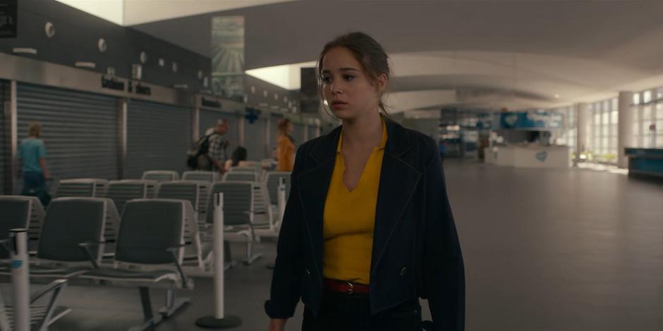 Ava walks back through the ferry terminal and searches for JC.