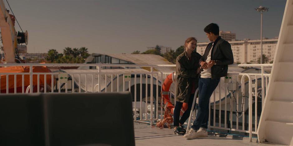 Ava and JC talk while leaning against the railing on the outside of the ferry.