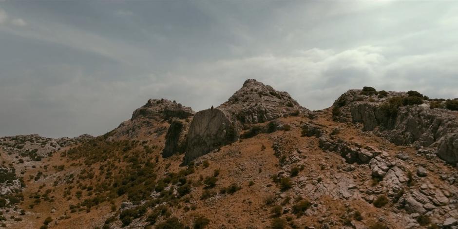 Ava sits perched on the edge of a cliff near the top of the hill.