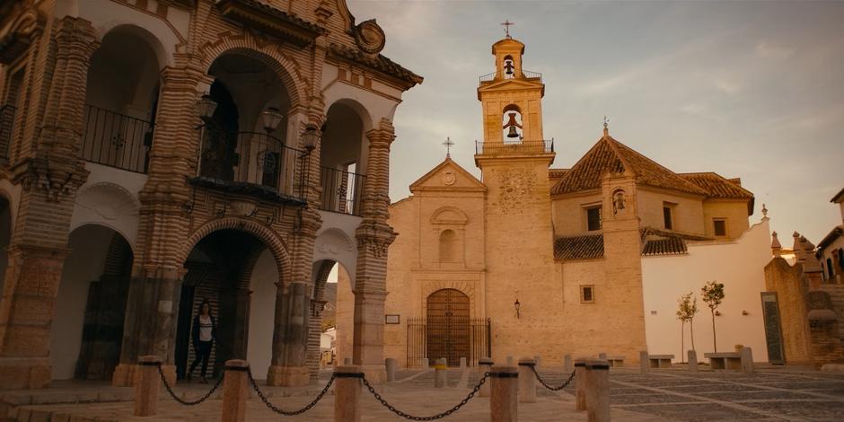 Ava emerges from the church as the sun rises and looks around the empty square.