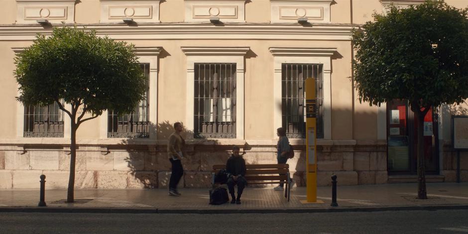 Beatrice sits on a bench waiting for the bus.